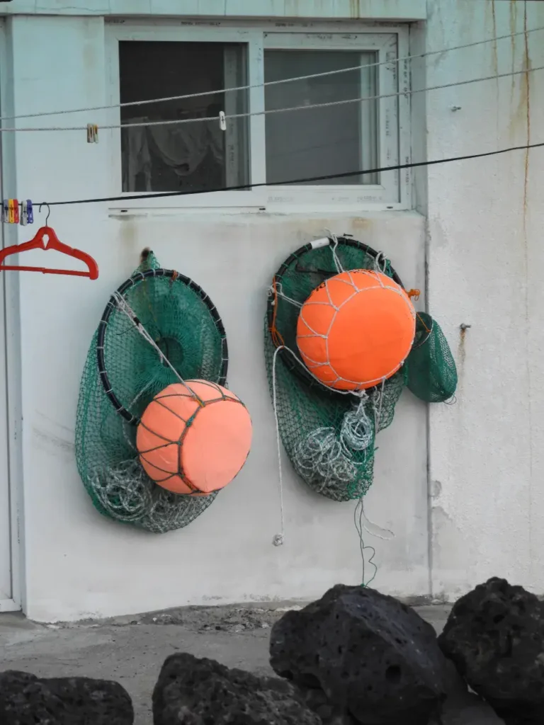 רשתות דייג המחוברות למצוף ציפה, תלויות לייבוש על קיר הבית ממנו יוצאות האניאו